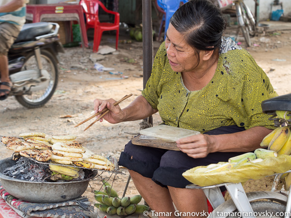 Mekong Delta (woman roasting glutinous rice covered bananas)